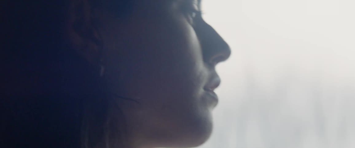 The woman is looking outside on a cloudy day