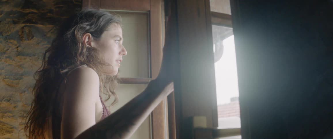 A woman opens the window and looks out