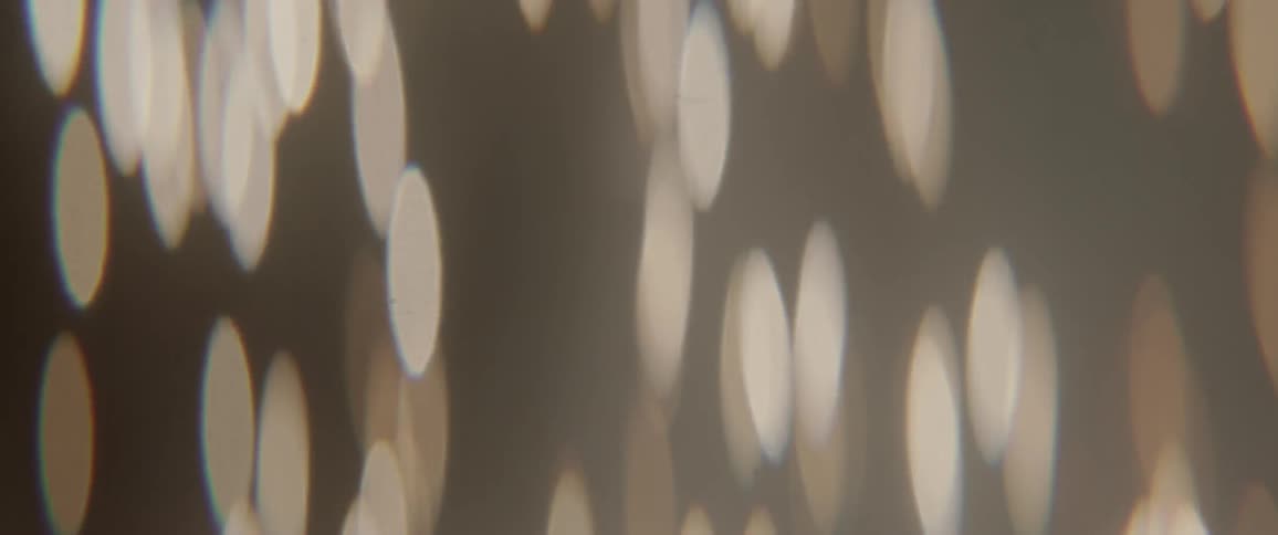 Circles of light rise and fall against a dark background