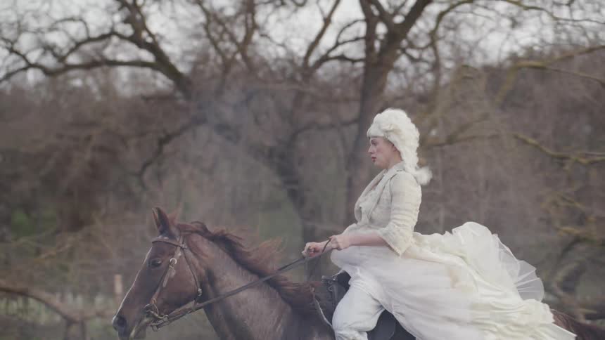 Woman in period costume rides horse