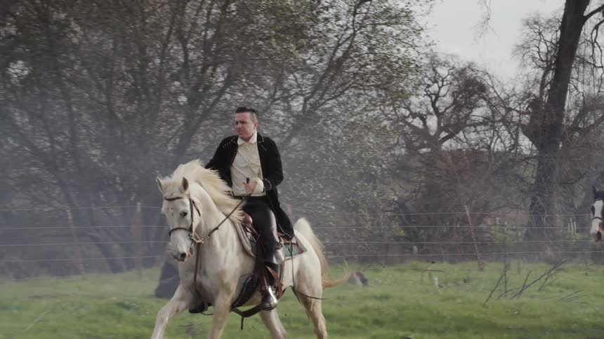 Man and woman in period costumes ride horses
