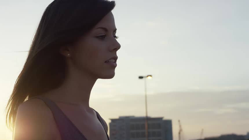 The wind blows a woman's hair at sunset