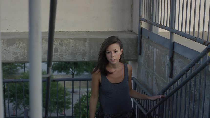 A brunette woman walking up a flight of outside stairs