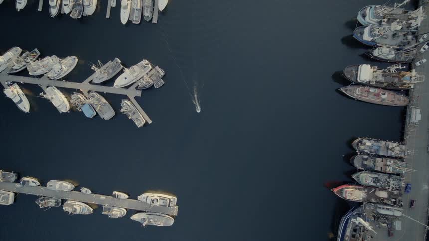 A dinghy leaves a small wake as it makes its way inside a marina