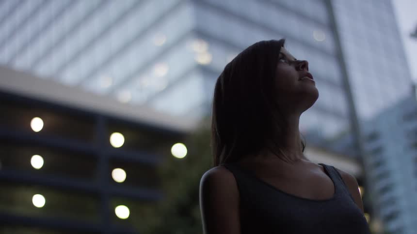 Woman looking up and admiring the tall buildings in a city
