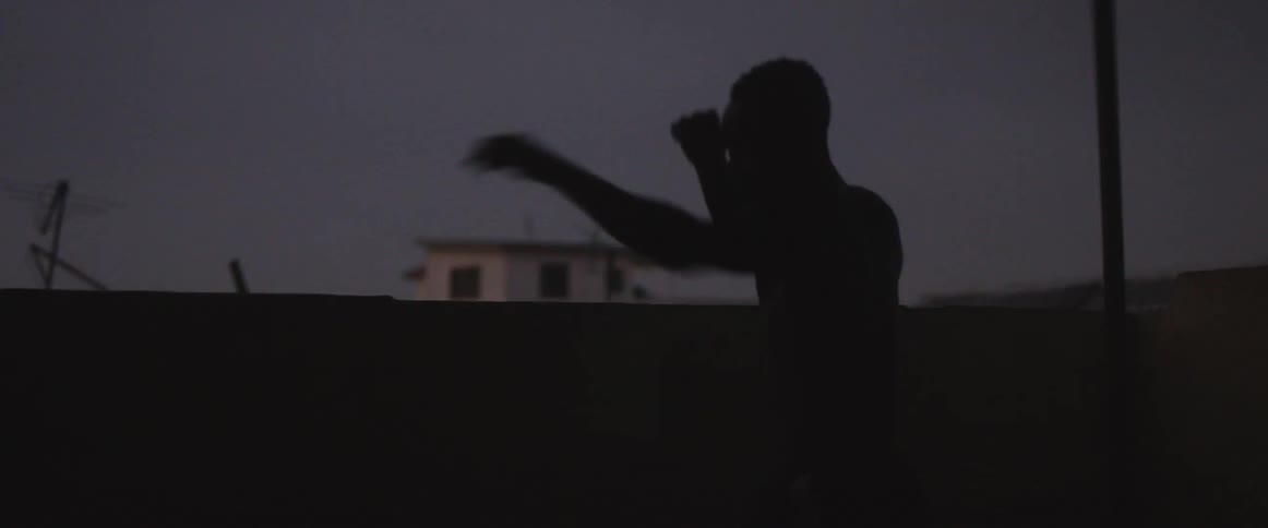 A boxer punches the air outside at night
