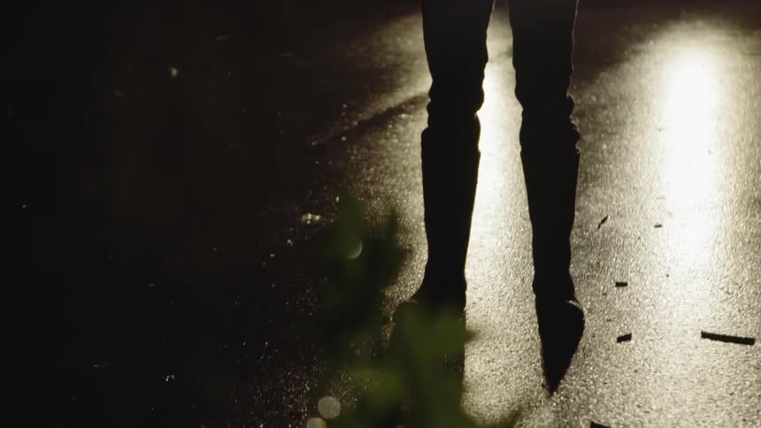 Man stands in the rain shining a flashlight at night
