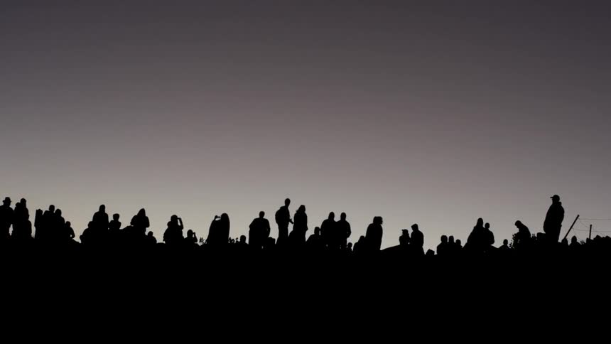 A group of shadowed people standing around