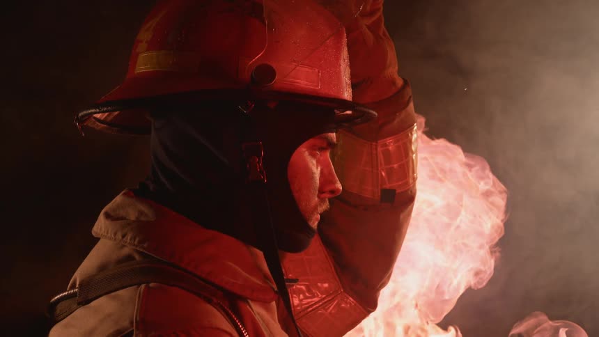 Firefighter putting on his helmet near fire