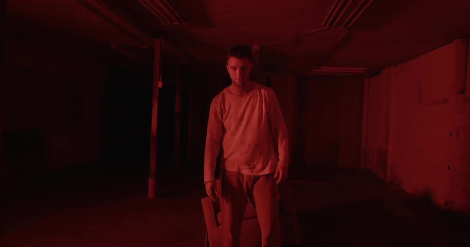 A man stands up straight in the dark hall