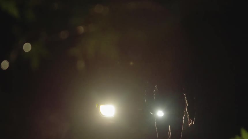 Man carries a flashlight as he walks in the dark in the rain