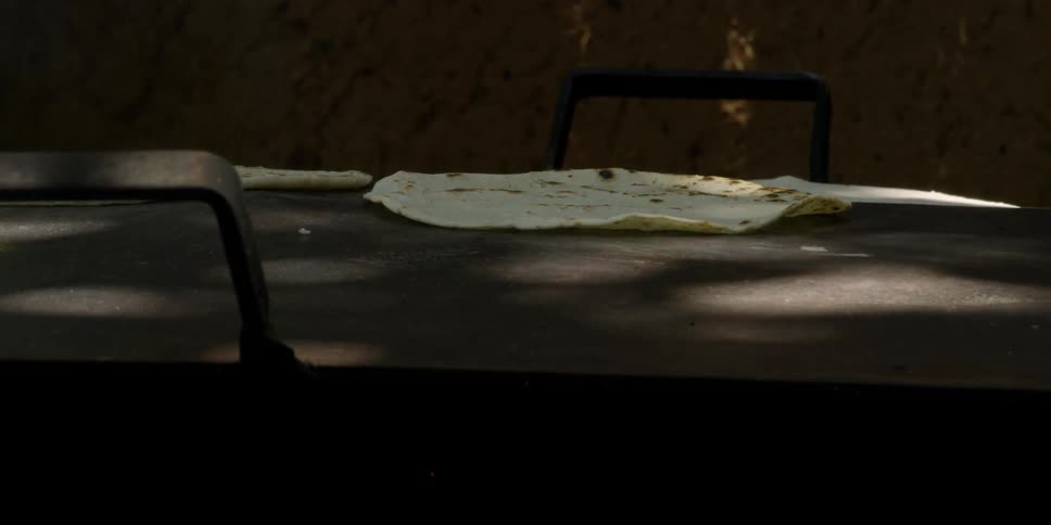 Person flipping tortillas on a blazing griddle
