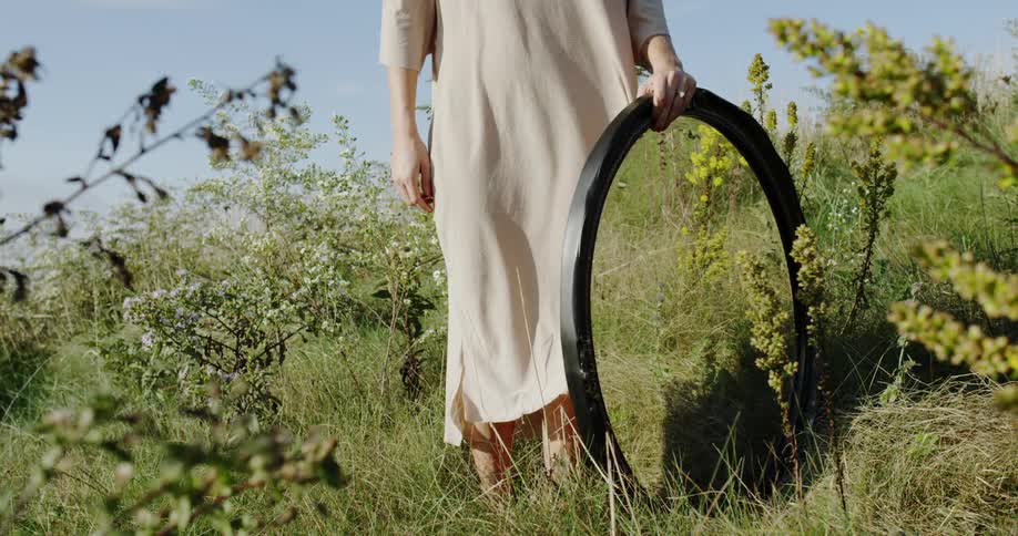 A woman holds a large hoop in the grass