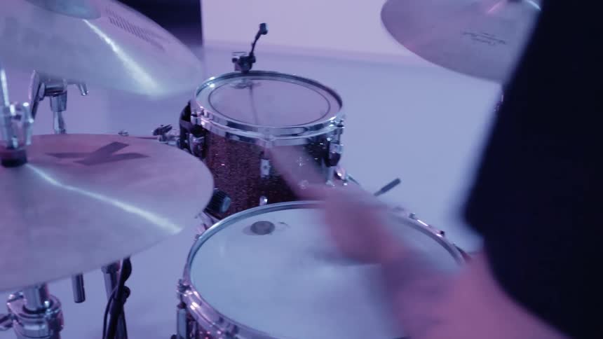 A man plays drums in an empty room