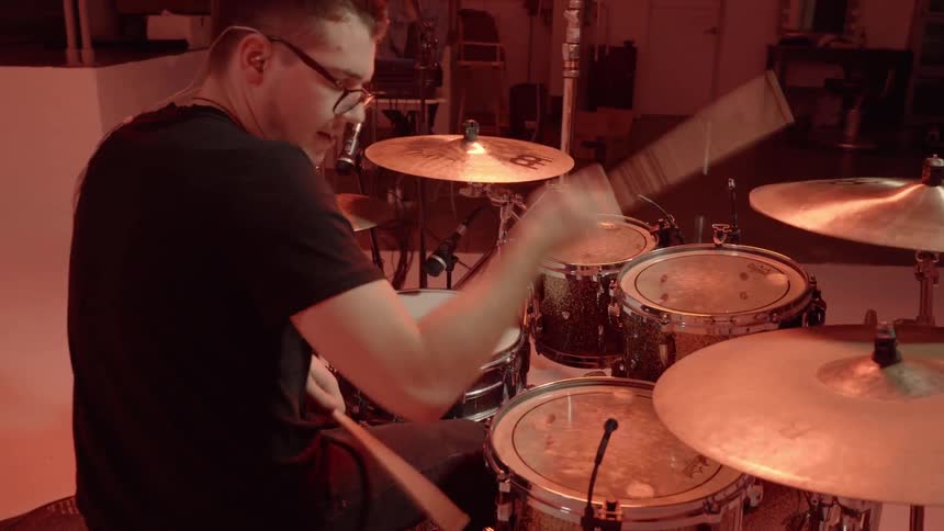 A man plays the drums in a studio
