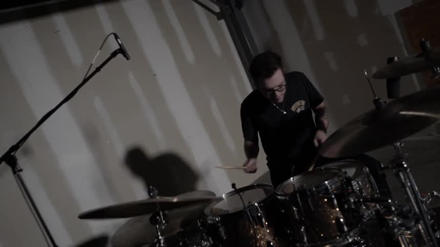 A man plays drums in an empty room