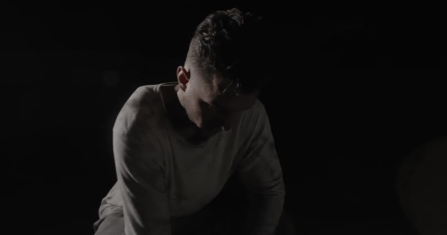 A man is breathing heavy as he squats inside in the dark