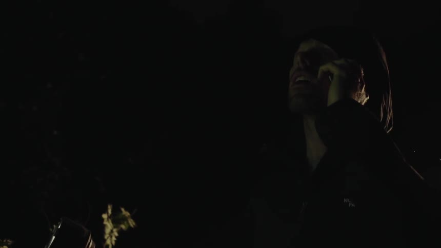 The man lifts his phone in the dark