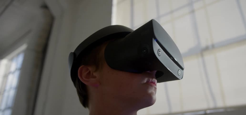 A man is using a virtual reality headset by the window