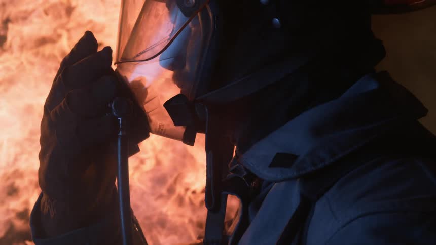 A firefighter holds his mask in the flames