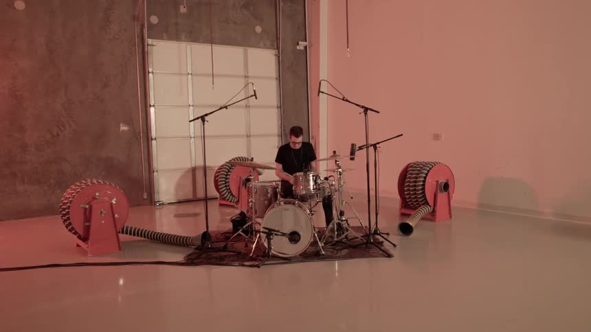 A man is dancing behind the drum set