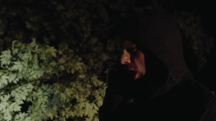 Man yelling into a cell phone at night near trees