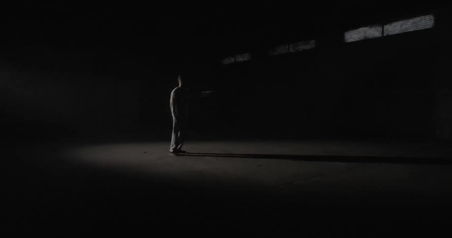 A man holds his arm up in a room with a strobing white light
