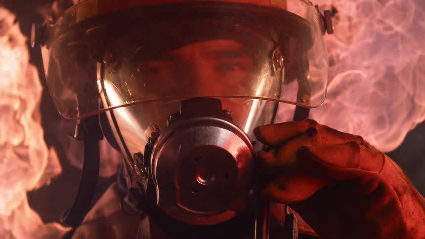 A firefighter adjusts his breather in the flames