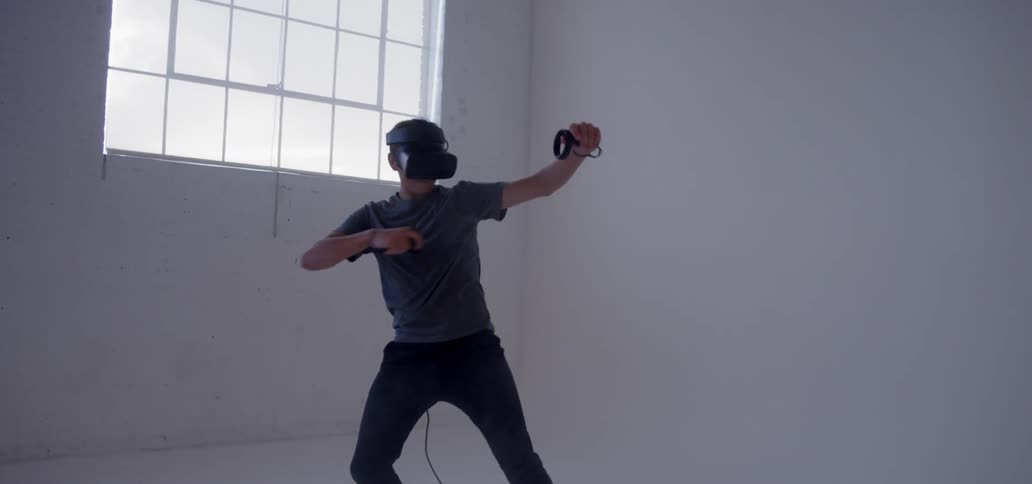 A young man uses a vr headset in an empty room