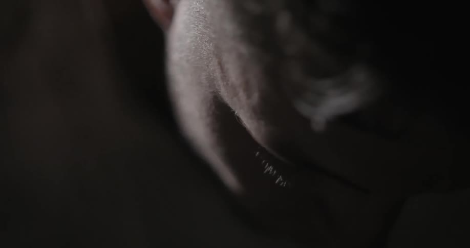 The man is leaning down in the dark