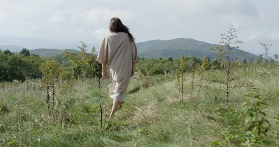 The woman walks through the tall grass