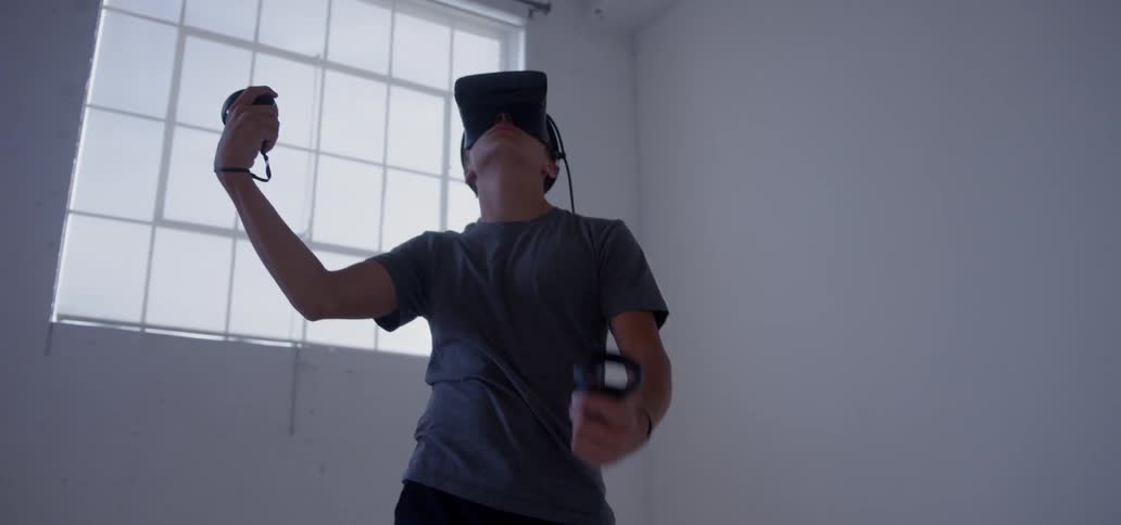A boy is using a virtual reality headset inside in daylight