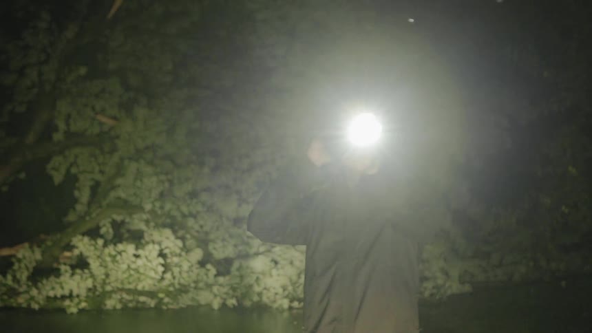 The man uses a phone as he shines a flashlight