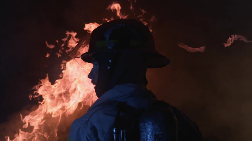 A firefighter stands by the fire