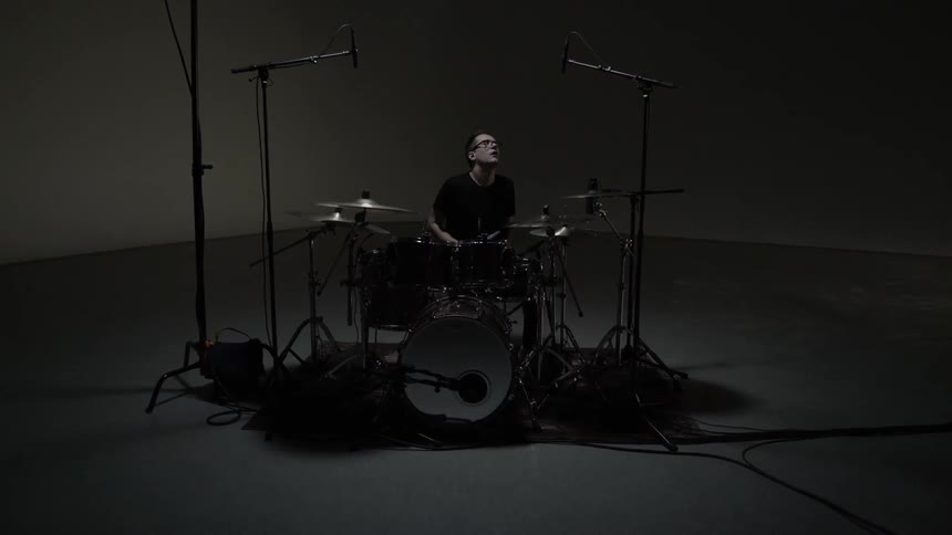 A man looks up while playing the drums