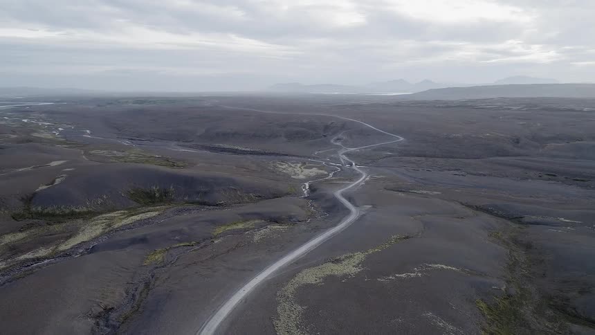 The road curves around these rocky hills