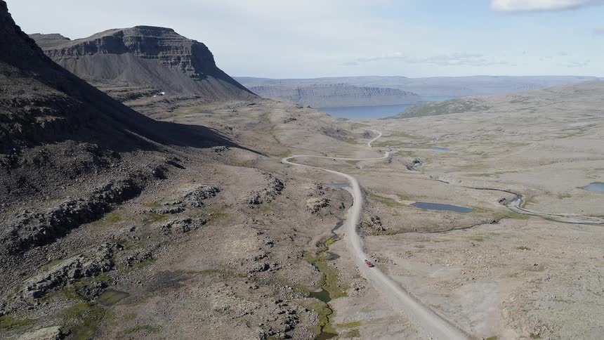 The car travels down the small desert road