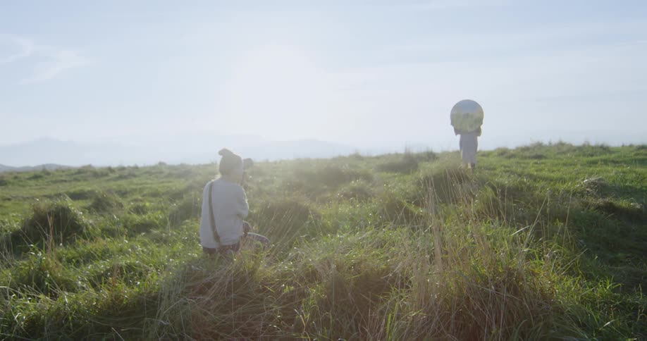 A woman is photographing someone in the grass