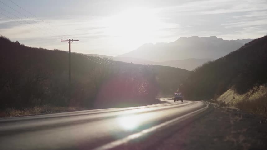 Vehicle travels down the winding road under the bright sun