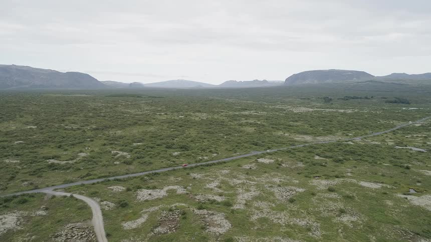 Cars drive on a country highway through a large flat area