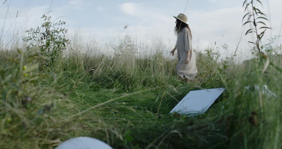 A woman walks through tall grass in a rural field
