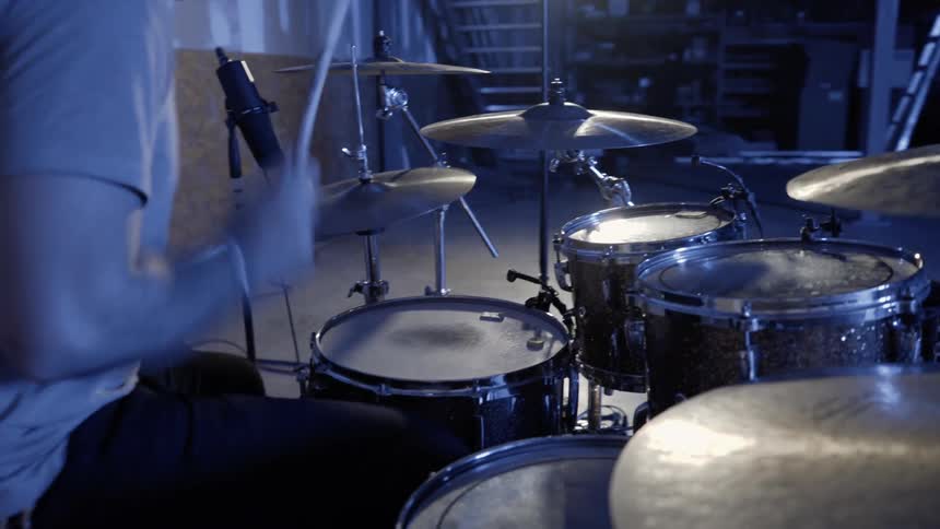 A drummer is playing drums indoors in daylight