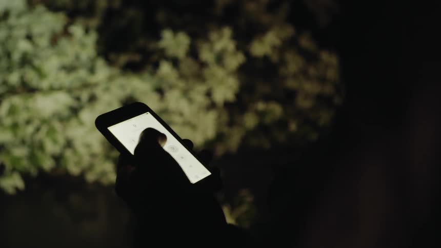 Man touches his cell phone screen as it rains