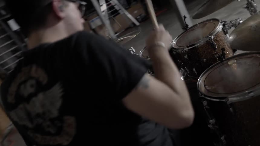A man is playing drums in a basement while the lights turn on and off