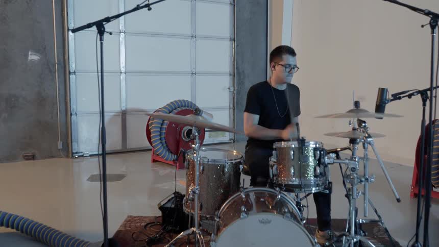 A man plays drums in a garage