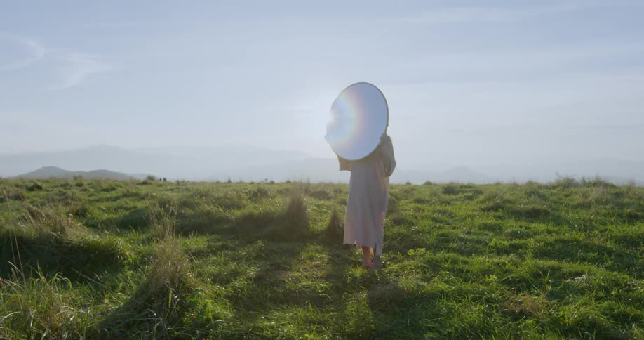 A woman holds a mirror up in the sun