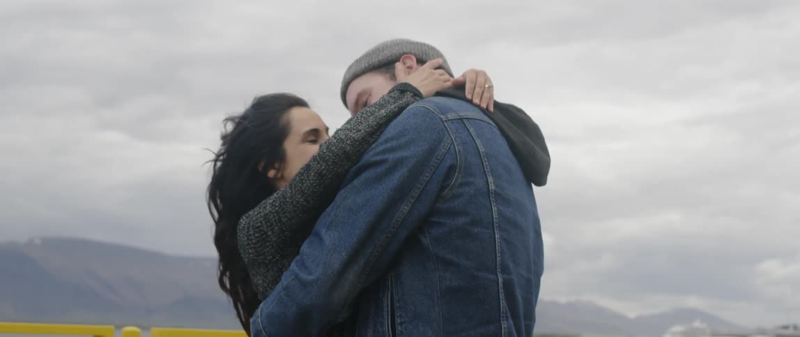 Lovers hug and flirt next to a mountain lake