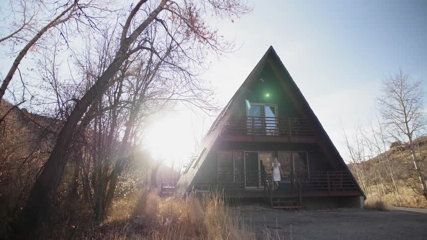 A woman enters a cabin on a sunny day