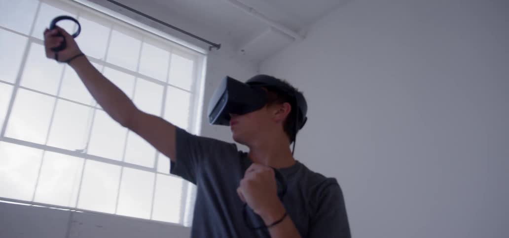 A young man uses a vr headset in an empty room