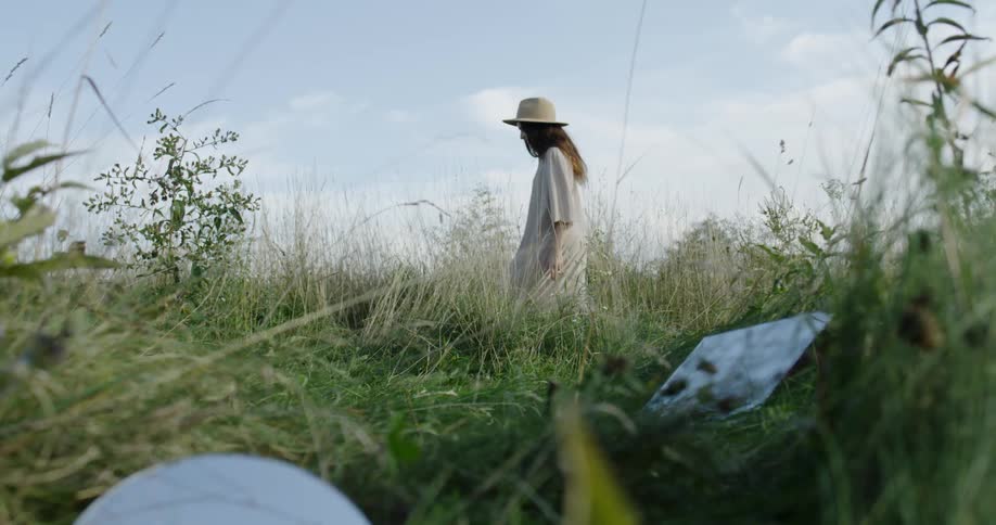 Woman walking through a grassy field during the day